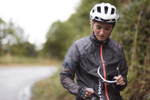 female cyclist riding her bike in the rain wearing BTWIN by Decathlon rain jacket