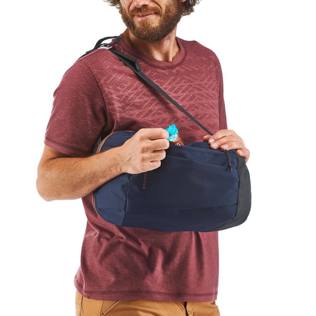 Man holding a navy blue bag over his shoulder with a white background