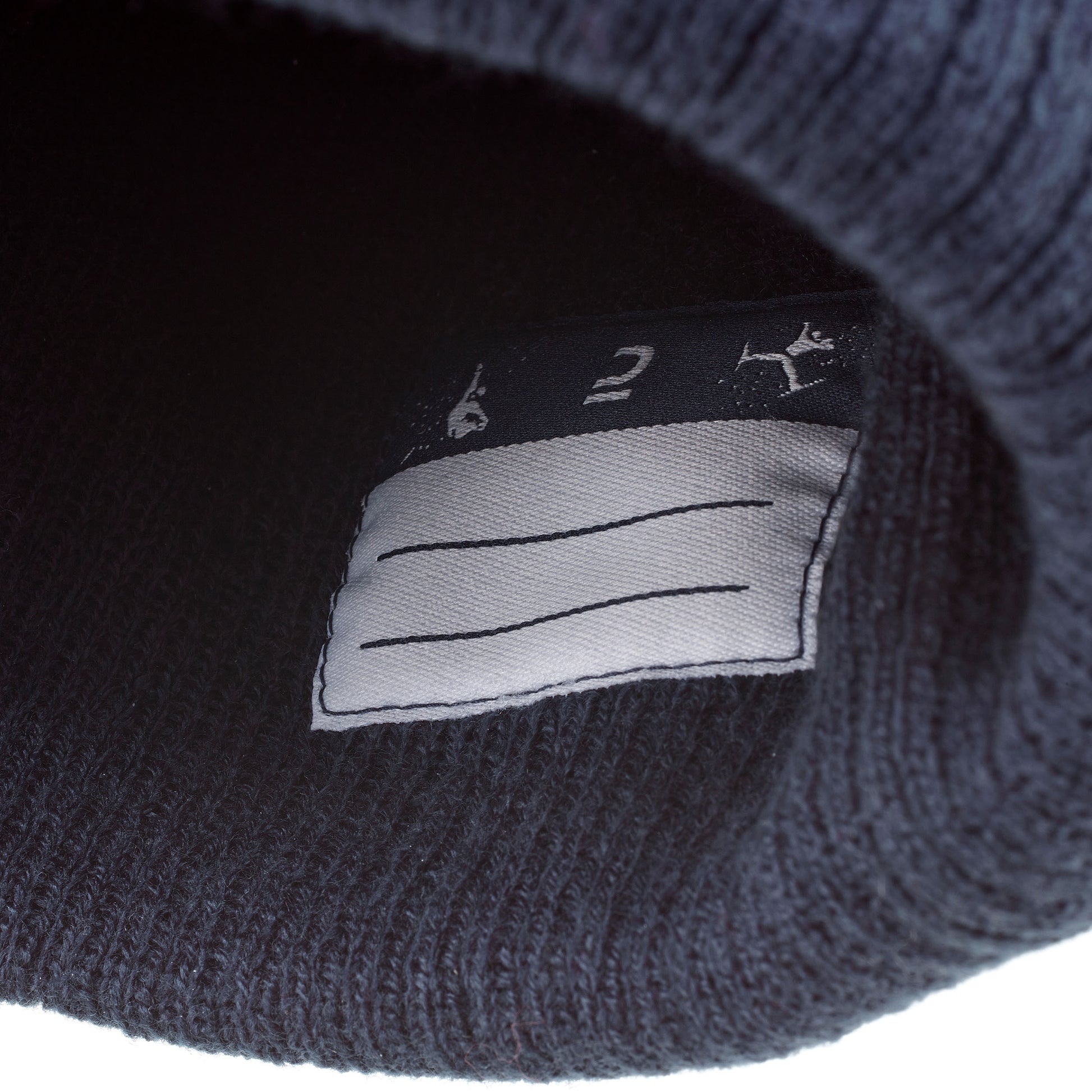 Close-up of a dark blue knit beanie with a label on a white background