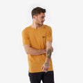 Man wearing a mustard yellow t-shirt with a small logo on a white background