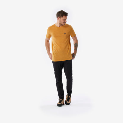 Man wearing a mustard yellow t-shirt and black pants on a white background