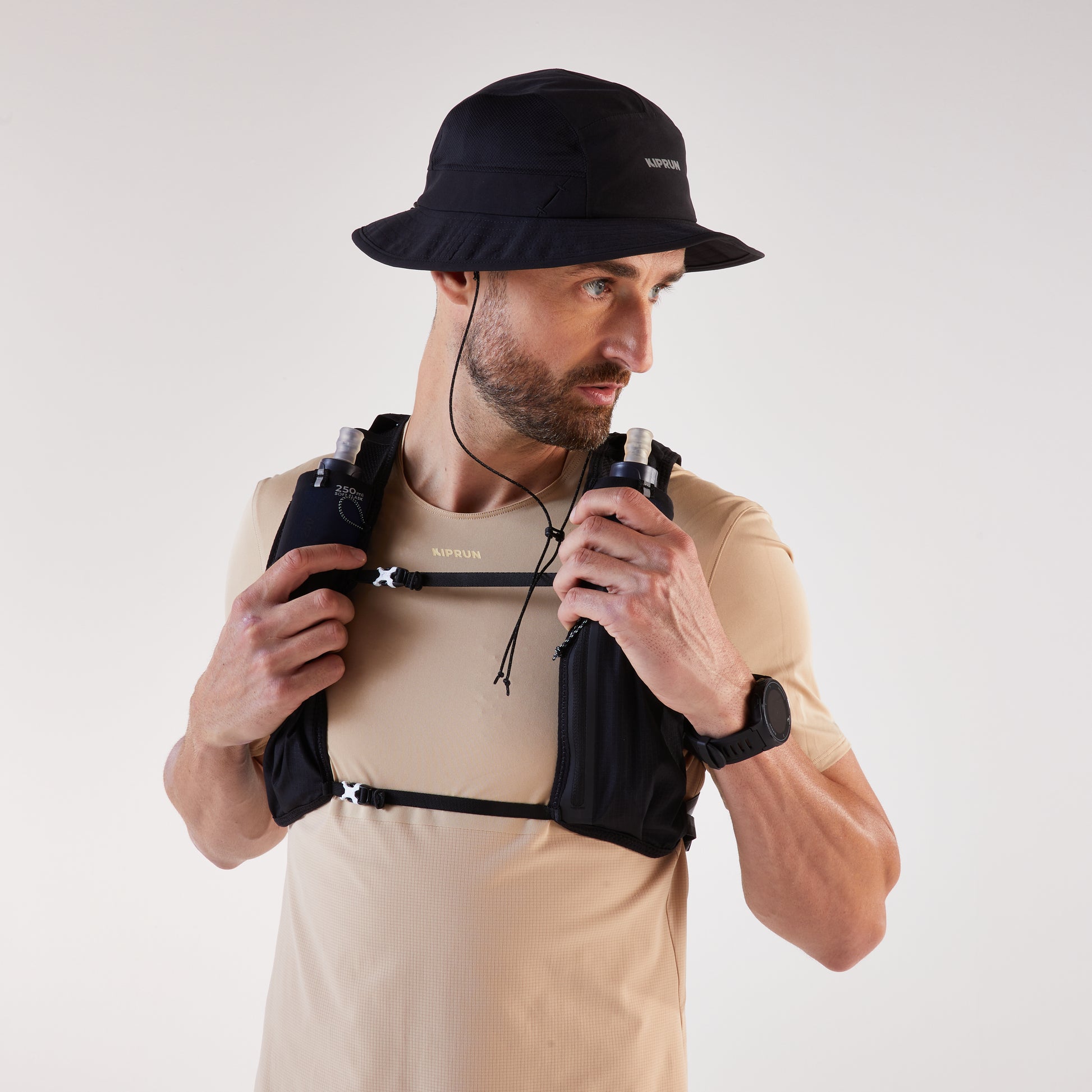 Man wearing a black hat and beige shirt with a black hydration pack on a white background