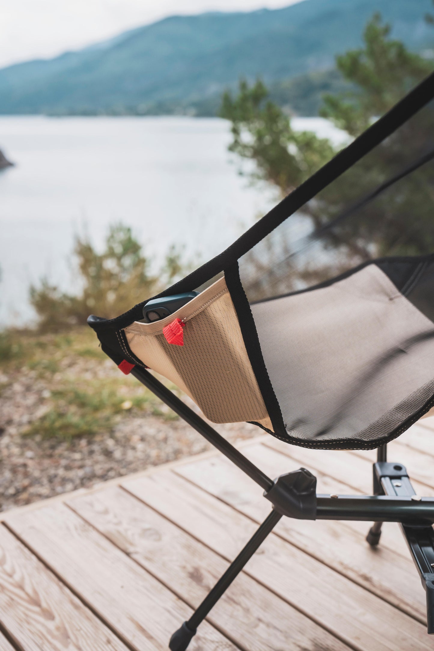 Chair on a wooden deck with a scenic view of a lake and mountains.